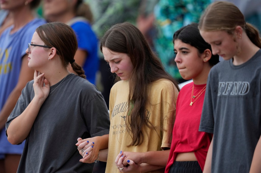 Attendees hold hands at a vigil for flood victims.