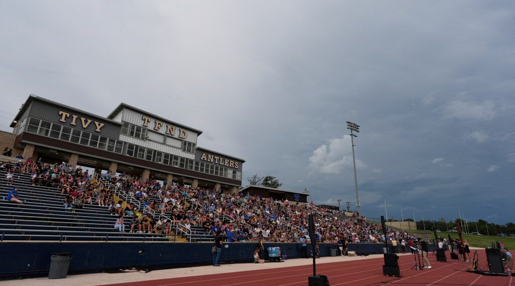 Hundreds came together at a Texas high school stadium to honor the lives lost in the floods. The mood was heavy—families held photos, candles flickered, and tears flowed. Then, without warning, Tom Brady walked onto the stage. No spotlight, no big entrance—just him. When he spoke, the crowd went silent. His voice cracked as he talked about loss, pain, and healing. People cried. They hugged each other. And in that moment, something shifted. Brady didn’t just bring words—he brought hope. Under the lights, grief began to turn into strength.