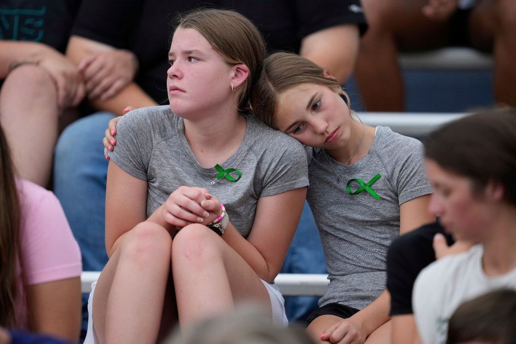 Two girls comforting each other at a vigil for flood victims.