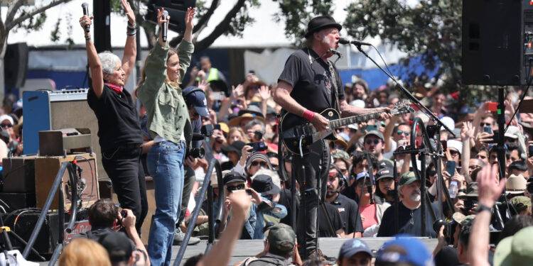 Just like she did in the ‘60s, Joan Baez still knows how to stop time with a single verse. At 84, she didn’t just take the stage — she owned it, turning protest into poetry and memory into fire. When she joined Neil Young for “Rockin’ in the Free World,” the anthem morphed — fierce, urgent, reborn. But it was the reprise, with Maggie Rogers and a thunderous chant of “Take America Back,” that turned heads — and hearts. Bernie Sanders nodded. AOC wiped away a tear. And somewhere in the crowd, an old activist whispered, “We’re not done yet.”