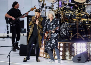 Together again — twenty years after that legendary rooftop moment at Buckingham Palace. From the first stomp of “We Will Rock You,” it was less an opening act and more a royal thunderclap, rolling across London’s summer night. Adam Lambert’s fire met Brian May’s soaring guitar, while Roger Taylor’s drums beat like the unshakable pulse of a nation — each note thick with history and adrenaline. Around them, the Platinum Jubilee’s three glittering stages shone with Elton John, Diana Ross, Andrea Bocelli, and a chorus of global icons, but this was the spark that lit it all. By the final roar of “We Are the Champions,” 22,000 voices rose as one — breathless, united, and certain they had just seen history repeat itself in the grandest, most glorious way