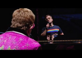 Fans were treated to a special surprise at the 95th show of Elton John’s Farewell Yellow Brick Road tour in Hove, UK, when under the summer sky the piano waited — but this time, Elton wasn’t alone. From the shadows stepped Taron Egerton, the man who had just brought Elton’s life to the big screen in ROCKETMAN, joining him not as a character but as himself. It was the first time since the tour began in September 2018 that Elton had shared his stage with a guest, and together they delivered a once-in-a-lifetime “Your Song” that blurred the lines between film, memory, and living legend